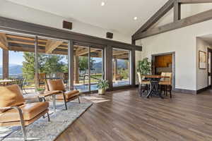 Living area featuring a mountain view, dark wood-style flooring, high vaulted ceiling, beamed ceiling, and recessed lighting