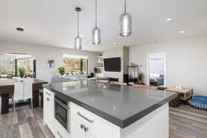 Kitchen featuring dark countertops, open floor plan, hanging light fixtures, and recessed lighting