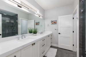 Bathroom featuring double vanity, a shower stall, and dark tile patterned floors