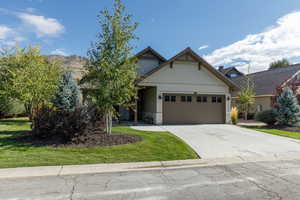 Craftsman house with stone siding, driveway, an attached garage, and a front yard