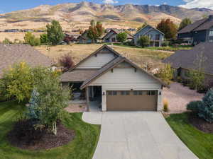 Craftsman house with a front lawn, concrete driveway, a mountain view, and an attached garage