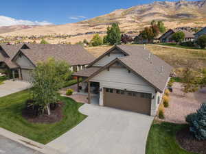Craftsman-style house featuring stone siding, a garage, driveway, a mountain view, and a front yard