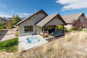 Rear view of property with stone siding, a patio, roof with shingles, and a mountain view