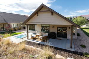 Back of house featuring a patio area, stone siding, an outdoor hot tub, a mountain view, and an outdoor living space
