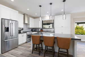 Kitchen with stainless steel appliances, a breakfast bar area, tasteful backsplash, decorative light fixtures, and recessed lighting