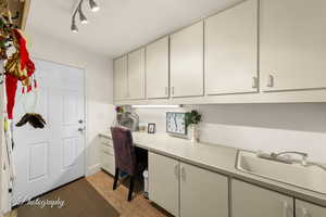 Office area with built in desk, light wood-style floors, and rail lighting