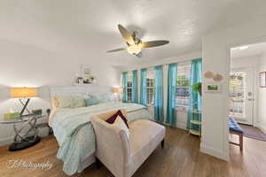 Bedroom with a textured ceiling, a ceiling fan, wood finished floors, and access to outside