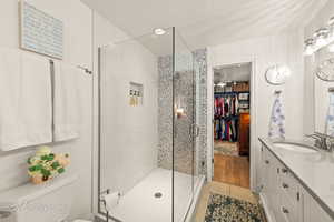 Full bathroom with a walk in closet, vanity, a stall shower, a textured ceiling, and light tile patterned flooring
