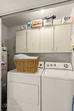 Laundry room featuring a textured ceiling, washing machine and dryer, cabinet space, and electric water heater