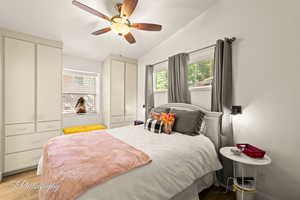 Bedroom featuring two closets, multiple windows, light wood-style flooring, and a ceiling fan