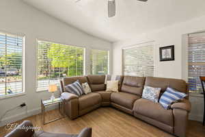 Living area featuring lofted ceiling, wood finished floors, a textured ceiling, and a ceiling fan