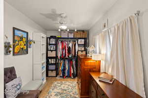 Bedroom featuring light wood finished floors, a desk, a walk in closet, and ceiling fan