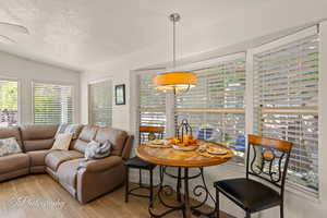 Dining space with a textured ceiling, wood finished floors, and lofted ceiling