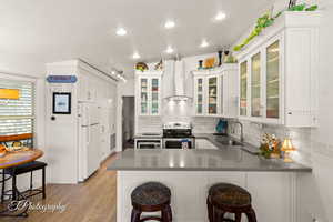 Kitchen featuring stainless steel range with electric stovetop, a textured ceiling, a peninsula, white cabinets, and freestanding refrigerator
