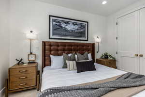 Carpeted bedroom with recessed lighting and a closet