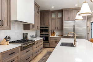 Kitchen with appliances with stainless steel finishes, pendant lighting, premium range hood, backsplash, and recessed lighting