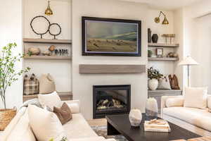 Living area featuring a tile fireplace, built in shelves, and wood finished floors