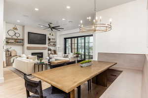 Dining area featuring a glass covered fireplace, recessed lighting, ceiling fan, light wood finished floors, and a chandelier
