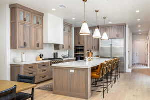 Kitchen with brown cabinets, hanging light fixtures, backsplash, appliances with stainless steel finishes, and recessed lighting