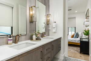 Full bathroom featuring double vanity, light wood finished floors, tasteful backsplash, recessed lighting, and ensuite bath