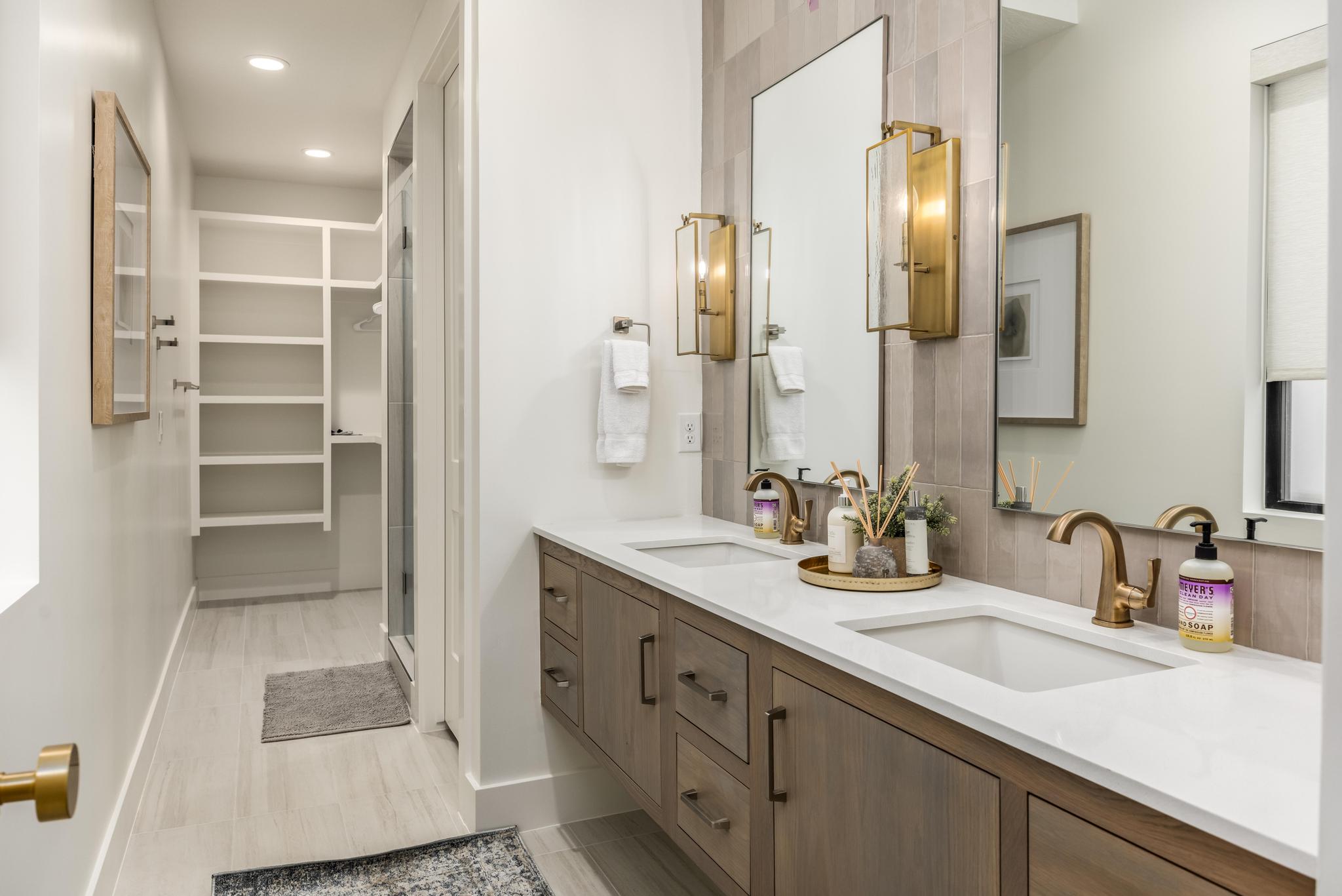 Full bath with double vanity, recessed lighting, a spacious closet, a stall shower, and light wood-style floors