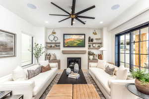 Living area featuring a large fireplace, ceiling fan, recessed lighting, and wood finished floors