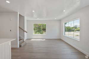 Unfurnished living room with light wood finished floors, healthy amount of natural light, recessed lighting, and stairs