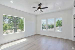 Empty room featuring light wood-style floors, healthy amount of natural light, recessed lighting, and a ceiling fan