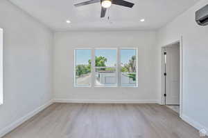 Empty room featuring light wood-style floors, recessed lighting, ceiling fan, and a wall mounted air conditioner
