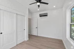 Unfurnished bedroom with recessed lighting, light wood finished floors, a closet, a ceiling fan, and a wall mounted AC