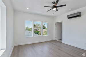 Unfurnished room with light wood-style floors, a wall mounted AC, recessed lighting, and ceiling fan