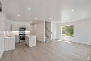Kitchen featuring a center island, open floor plan, stainless steel appliances, light wood-style floors, and recessed lighting