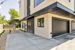 View of side of home featuring a fenced backyard, stone siding, and a garage