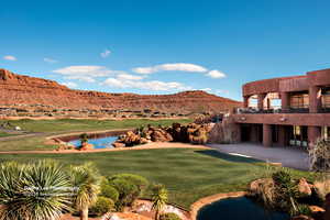 View of green lawn with view of golf course, a water and mountain view, a patio, and a balcony