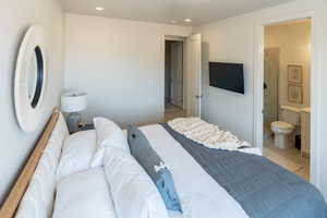 Bedroom with light tile patterned floors, recessed lighting, and ensuite bathroom