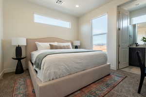 Carpeted bedroom with ensuite bath and recessed lighting