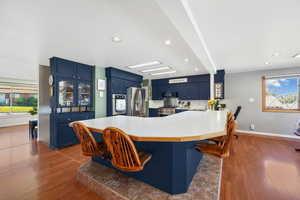 Kitchen with 'European blue' cabinets, light countertops, a peninsula, stainless steel appliances, and a kitchen breakfast bar.