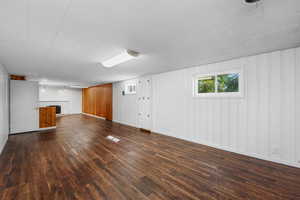 Daylight basement living room featuring dark wood-type flooring, bright paint and lighting.
