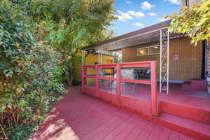 View of fenced wooden terrace, connected to covered patio.