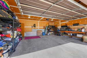 Large two car garage with automatic door, a workbench and storage racks.
