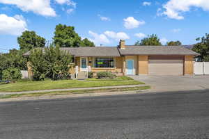 Rambler style home with a front lawn, peach tree, herb garden, brick siding, concrete driveway, an attached two car garage, and RV parking.