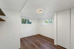 Daylight basement bedroom with dark wood-type flooring, three closets, and updated windows.