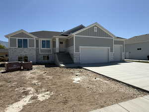Craftsman house featuring board and batten siding, driveway, stone siding, and an attached garage