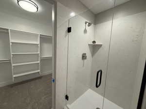Bathroom featuring dark colored carpet, a walk in closet, and a stall shower