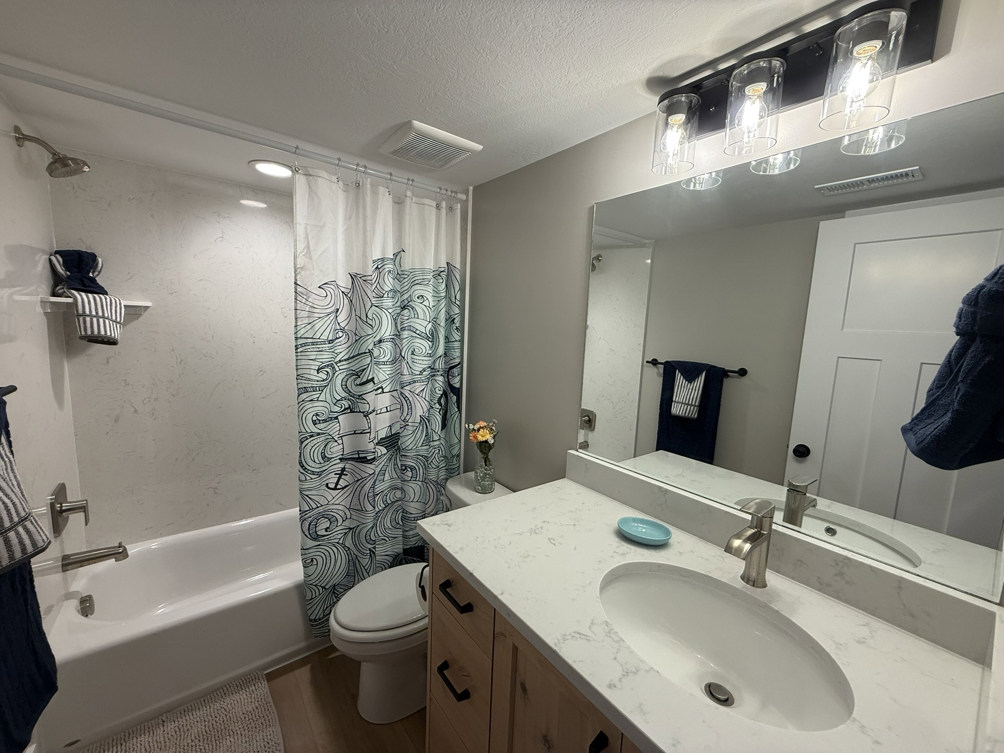 Bathroom with shower / bathtub combination with curtain, a textured ceiling, vanity, and dark wood-style flooring