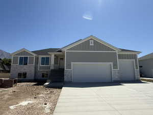Craftsman house featuring board and batten siding, a garage, driveway, and stone siding