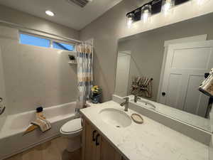 Bathroom with shower / bath combination with curtain, wood finished floors, and vanity