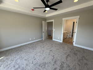 Unfurnished bedroom featuring recessed lighting, a raised ceiling, carpet, ceiling fan, and connected bathroom