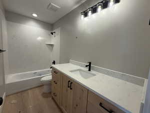 Bathroom featuring shower / washtub combination, vanity, light wood finished floors, and recessed lighting
