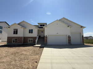 View of front of home featuring board and batten siding, driveway, an attached garage, and brick siding